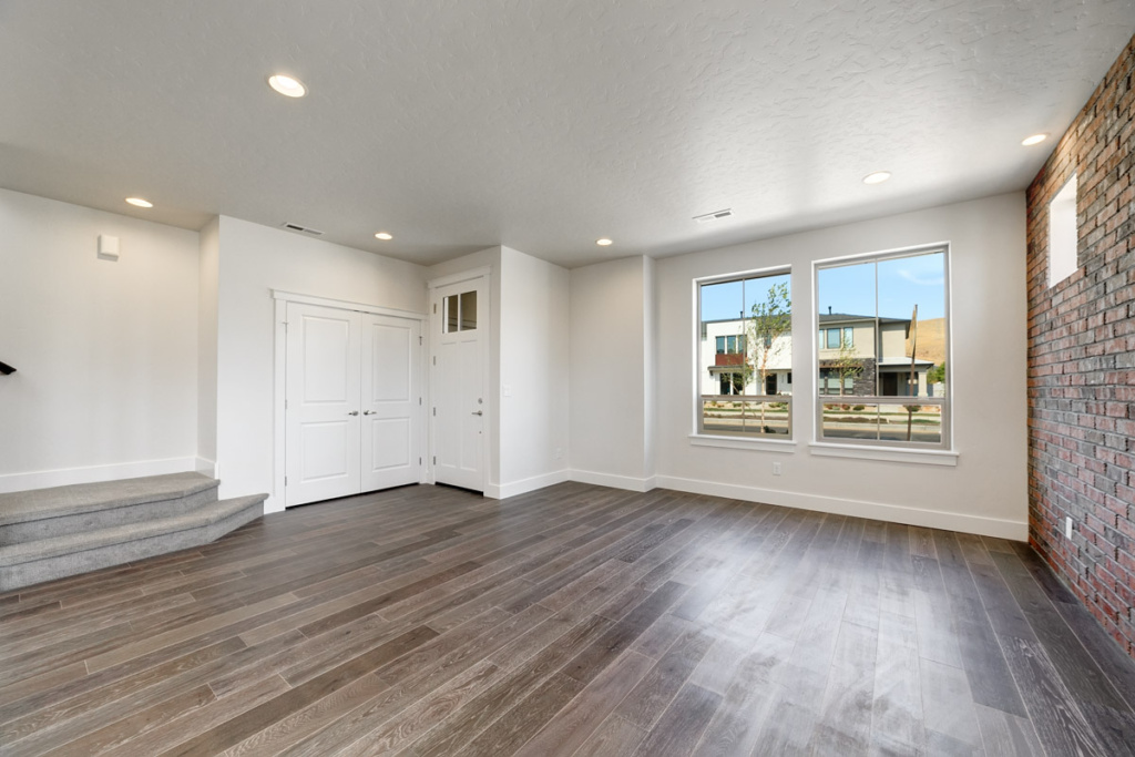 Spacious living room with brick wall detailing in a corner lot townhouse at The BLVD in Harris Ranch.