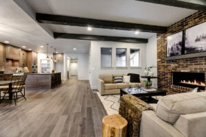 Photo of the open-concept living room and kitchen with a brick fireplace, exposed wood beam, and a gourmet kitchen.